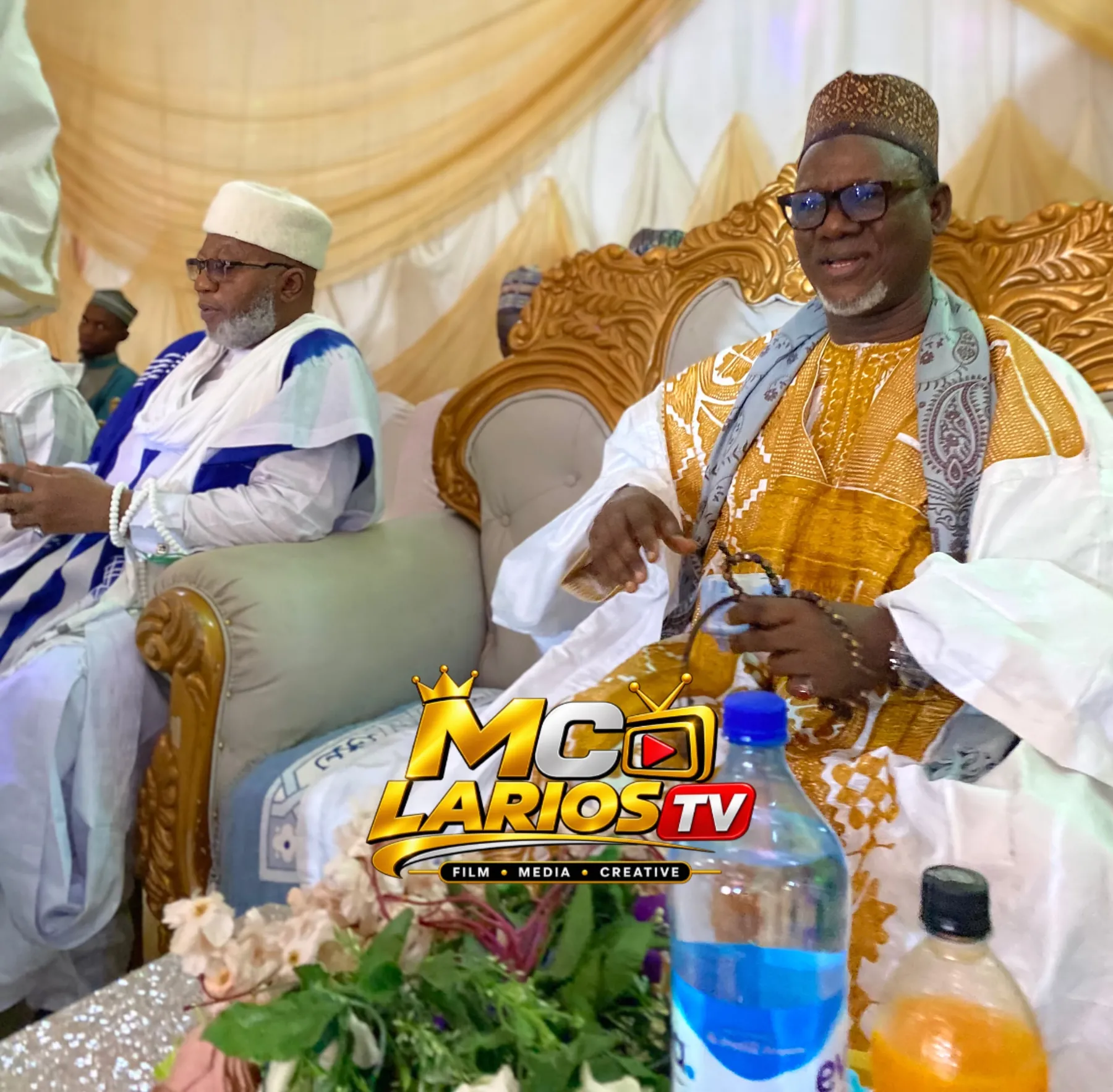 Two dignitaries seated on the high table, one in blue and white, one in white and gold