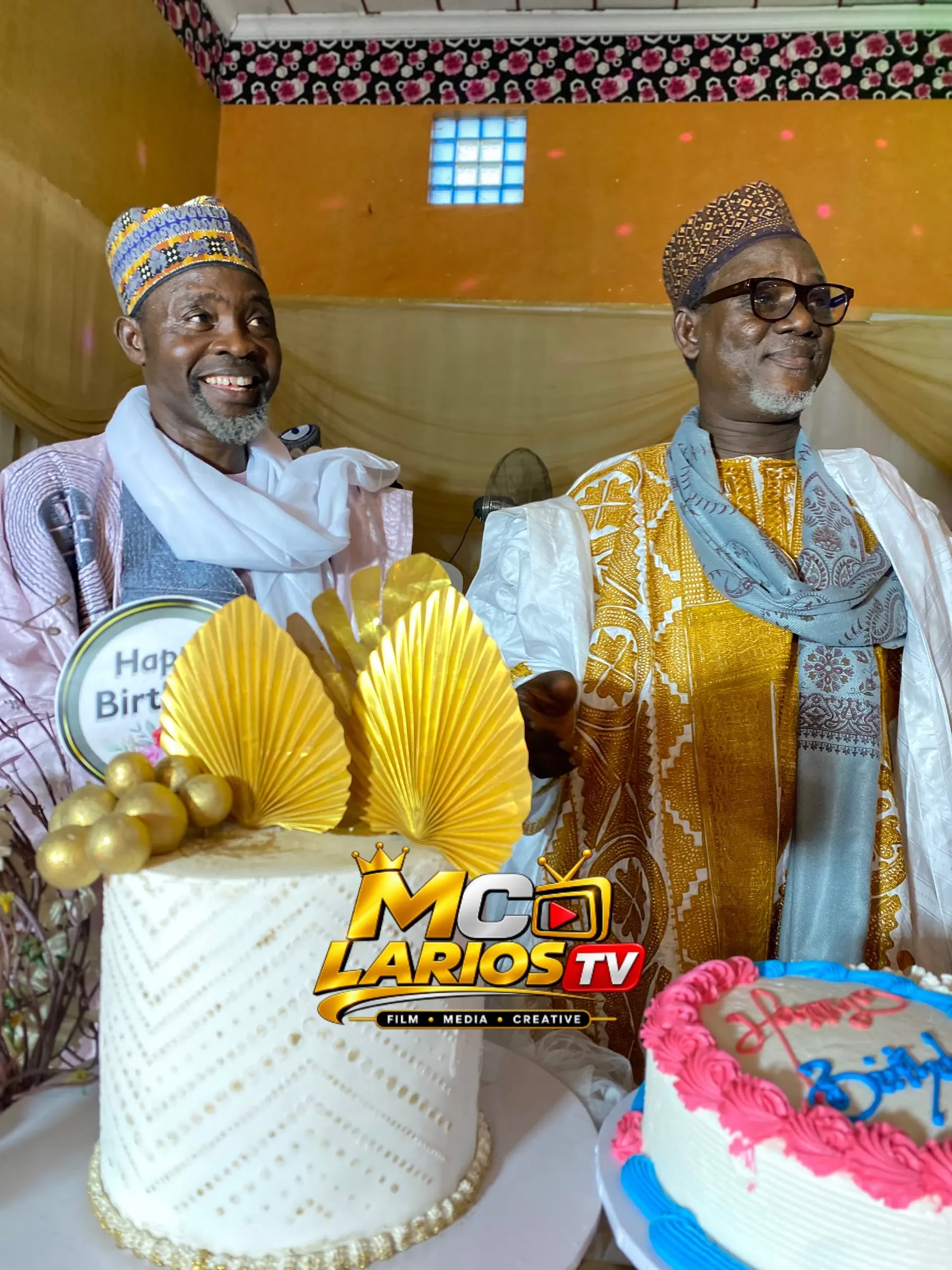 Two elders standing behind a decorated cake