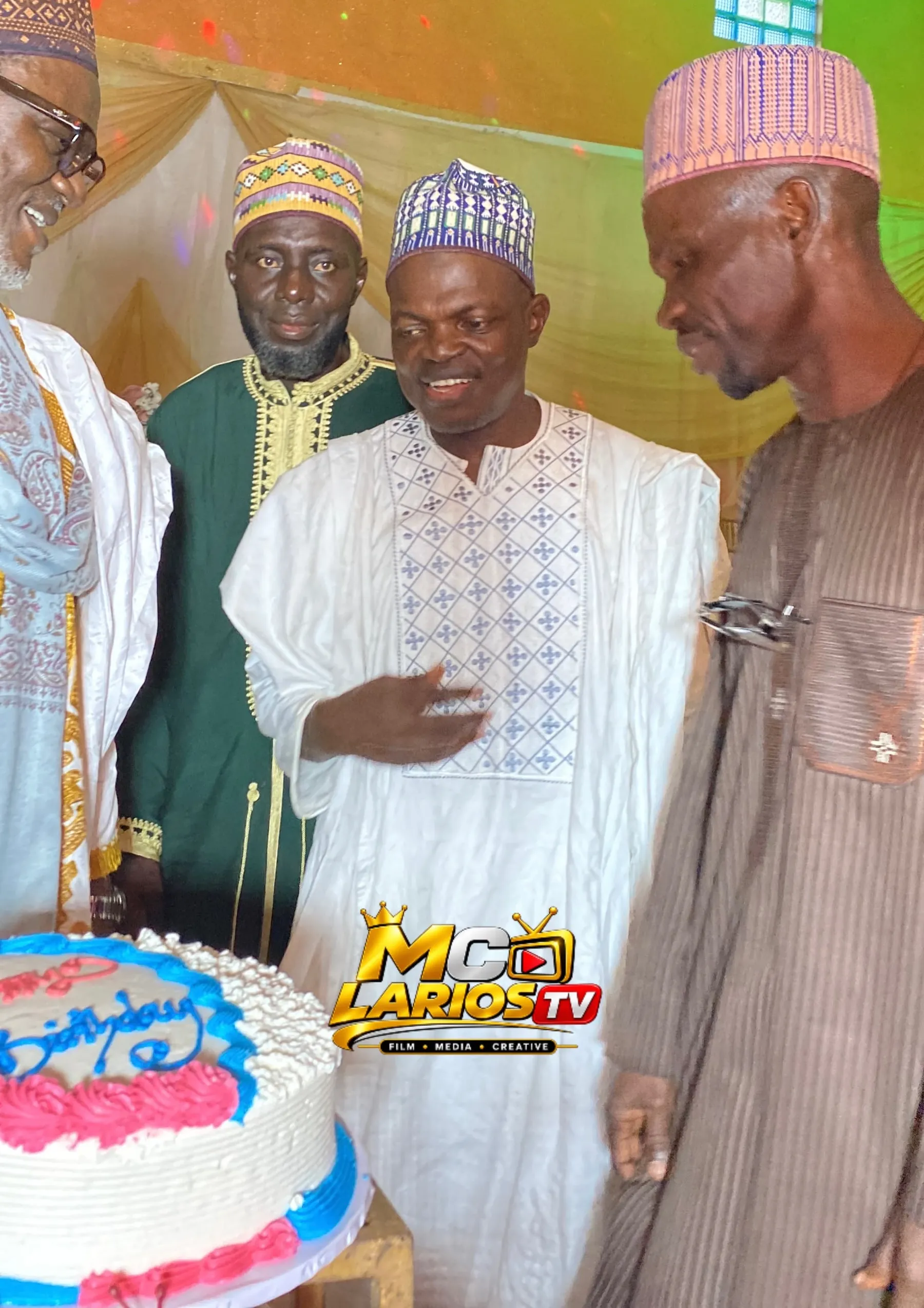 Guests in caps and robes standing around a cake