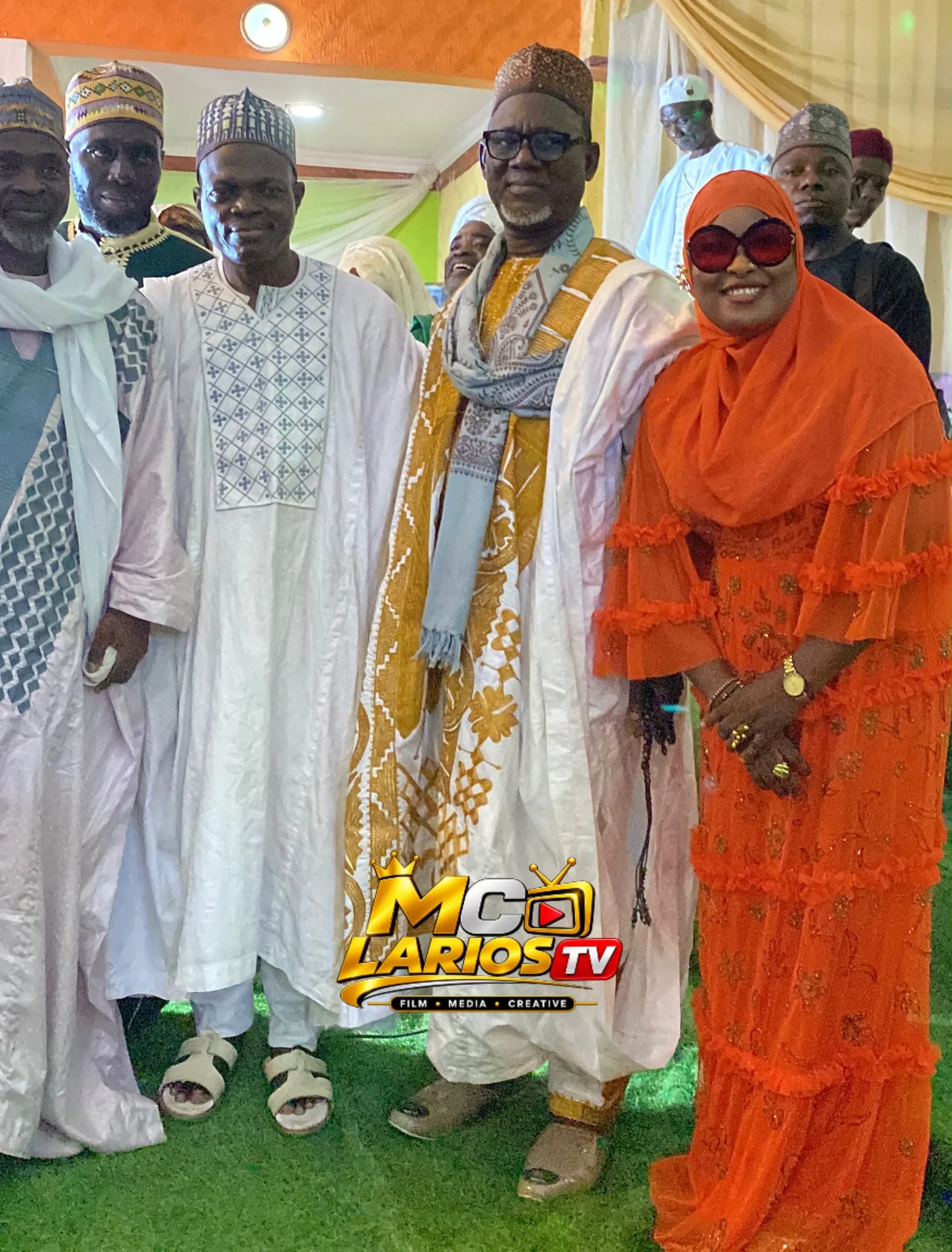 Guests in white, gold and orange standing together on green carpet