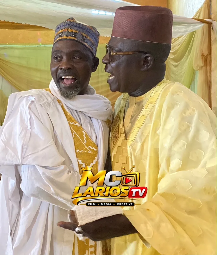 Two men in white and gold robes greeting each other warmly