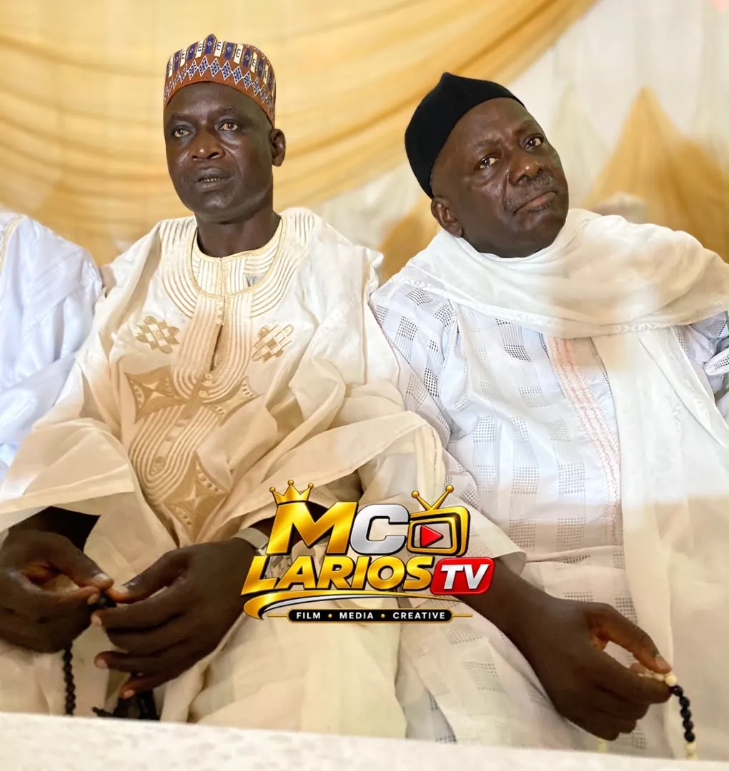 Two men in white robes seated, holding prayer beads