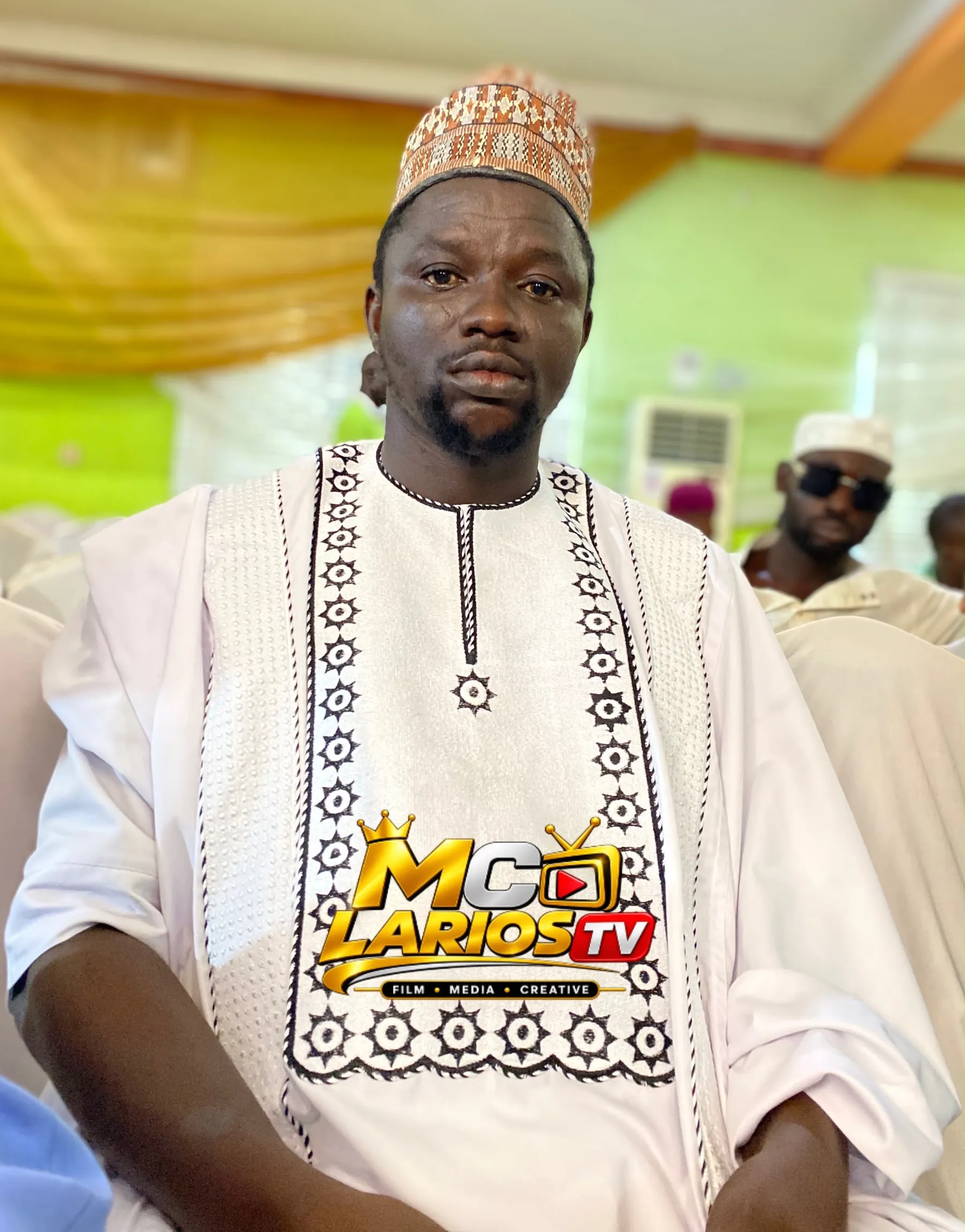 A man in an embroidered white kaftan and cap