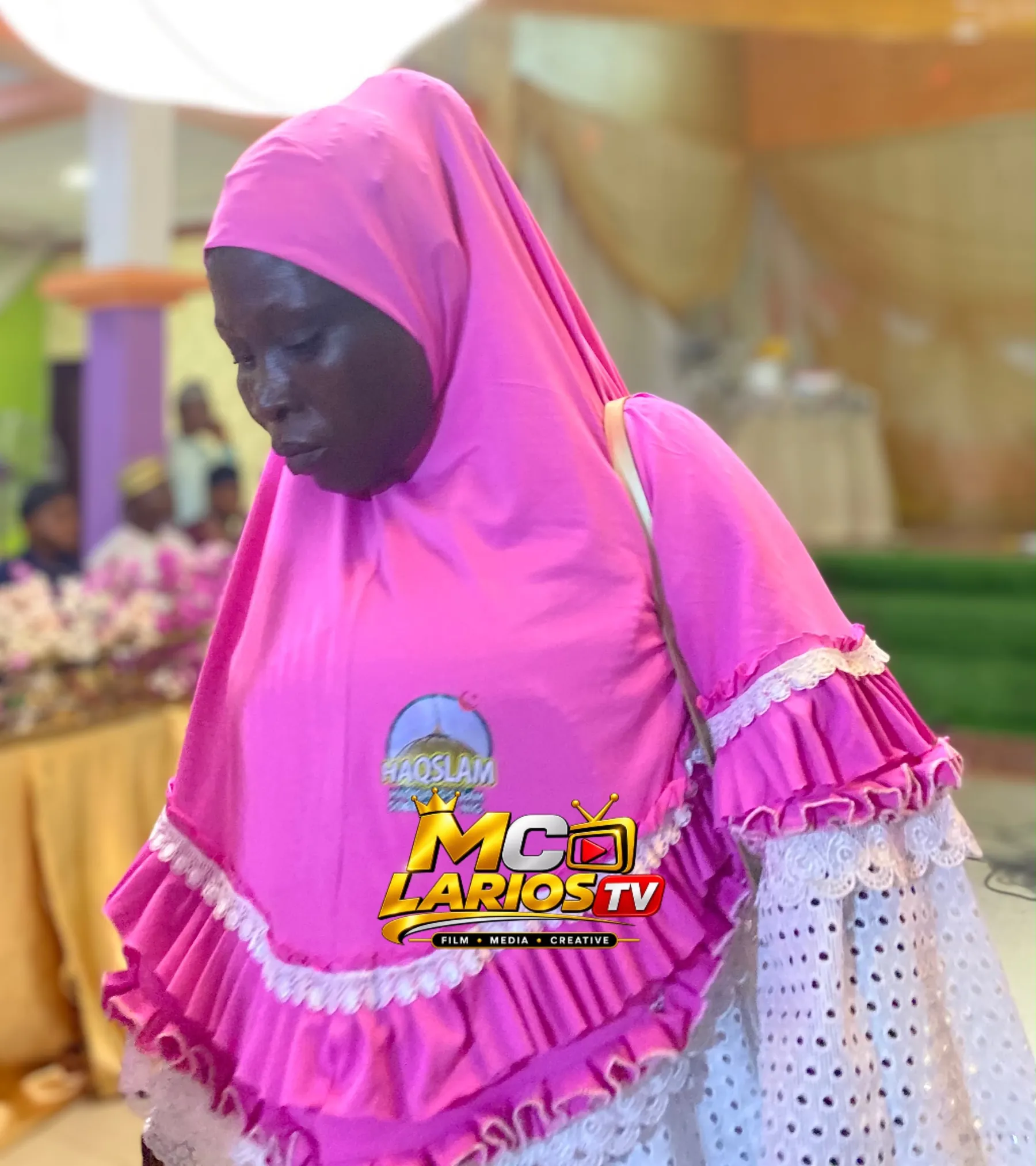 A woman in a pink hijab bearing the HAQSLAM emblem