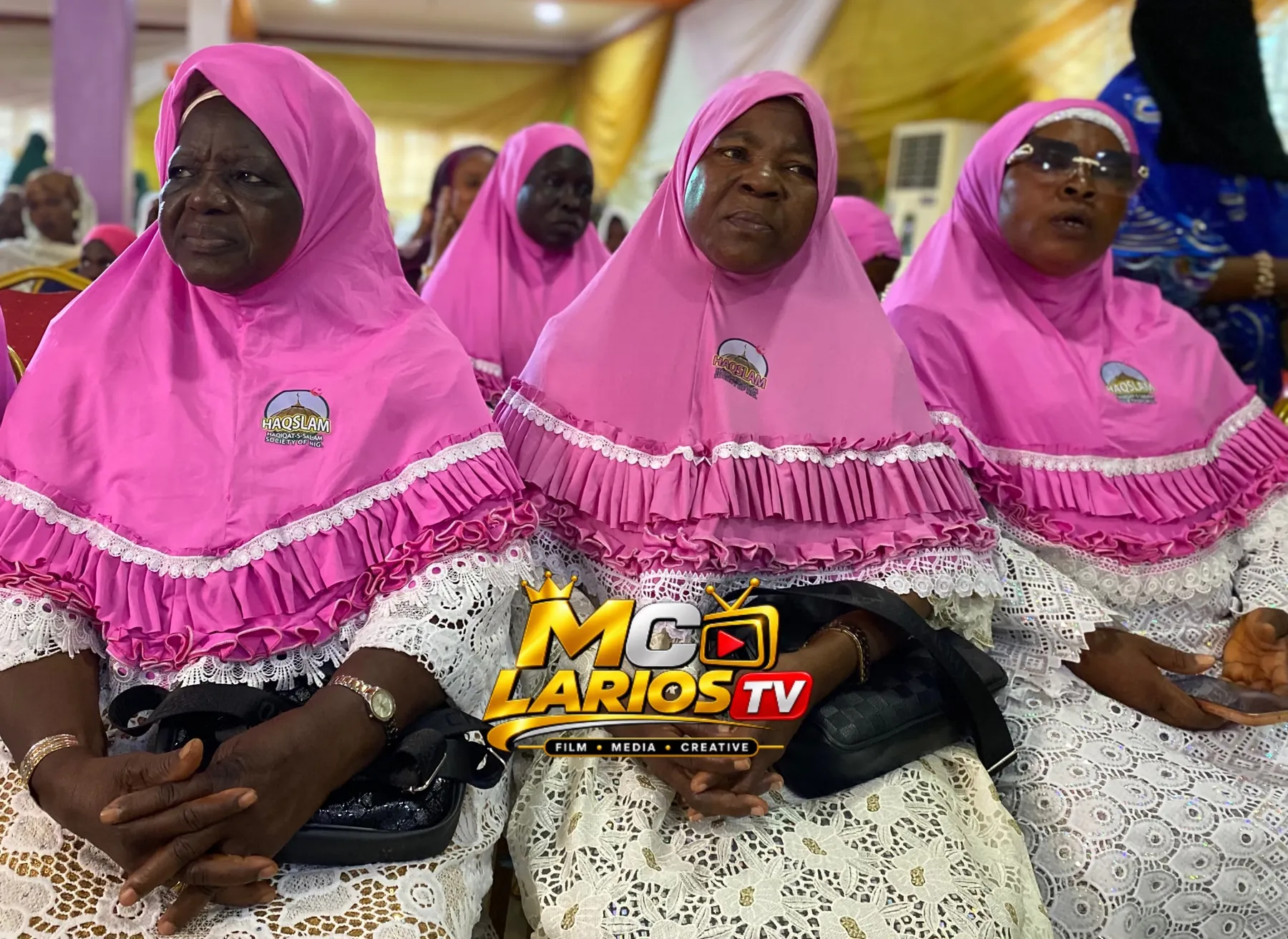 Women in pink hijabs seated in rows