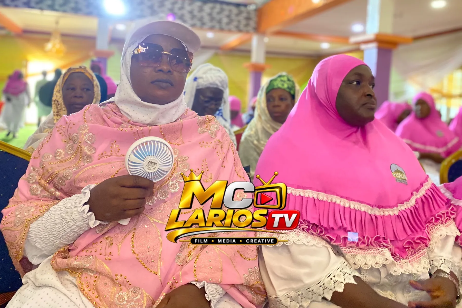 Women in pink and white seated in the audience