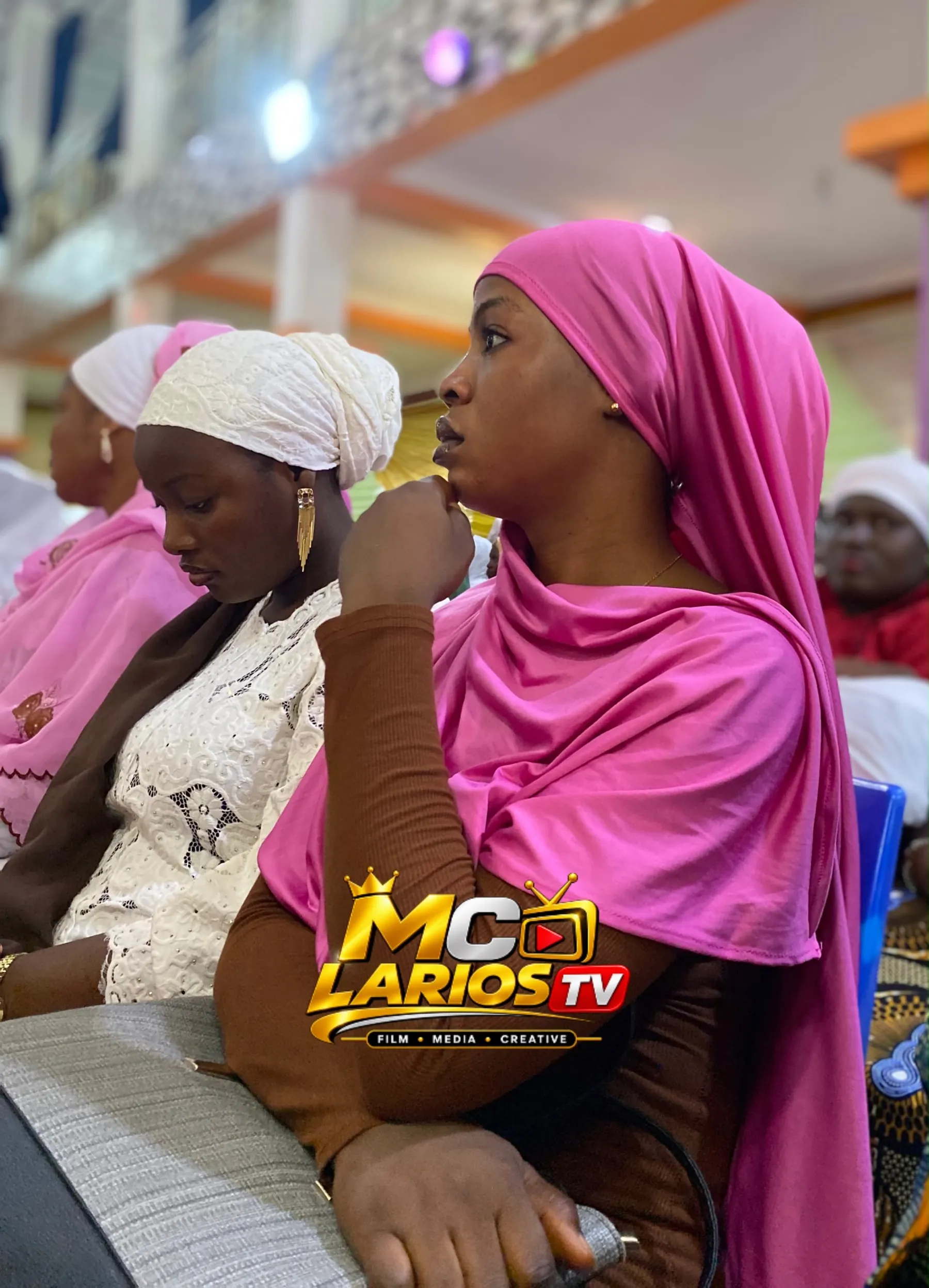 Two women in the audience, one in a pink hijab